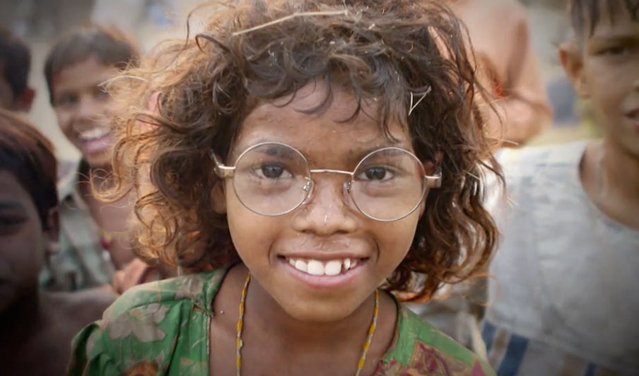 Indisches Mädchen trägt eine Brille und lächelt in die Kamera.