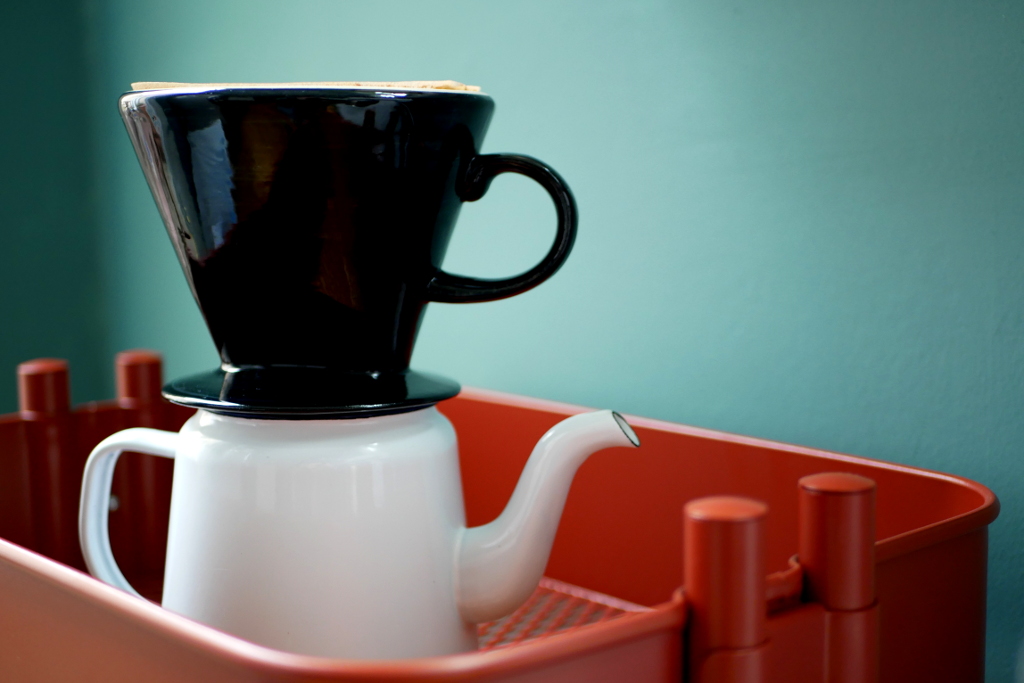 Foto kleine weiße Kaffeekanne und schwarzer Kaffeefilter