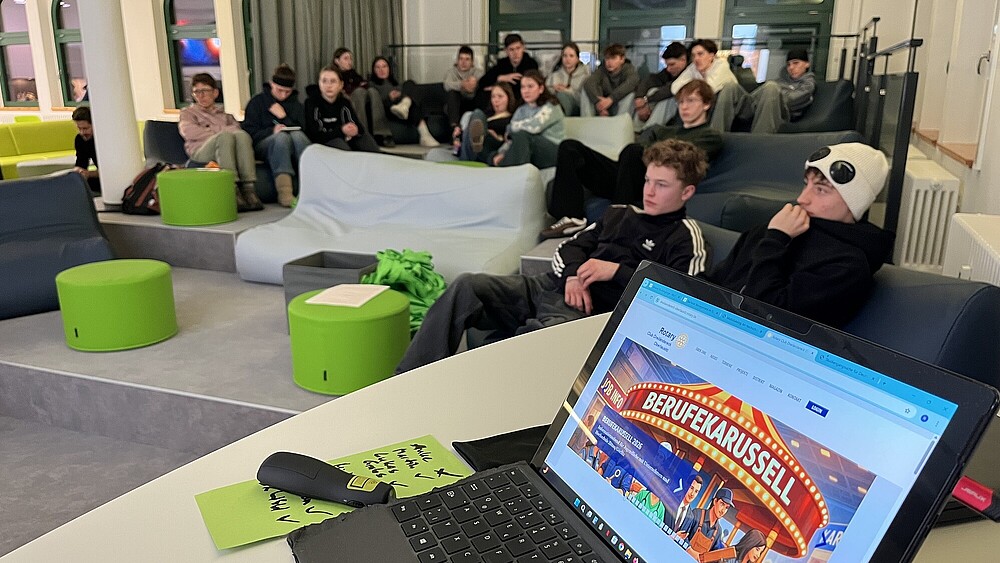Students sit on green sofas in the anteroom to the DLR School Lab.