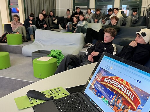 Schüler sitzen auf grünen Sofas im Vorraum zum DLR School Lab.