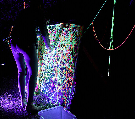 A woman stretches neon colors over a frame.