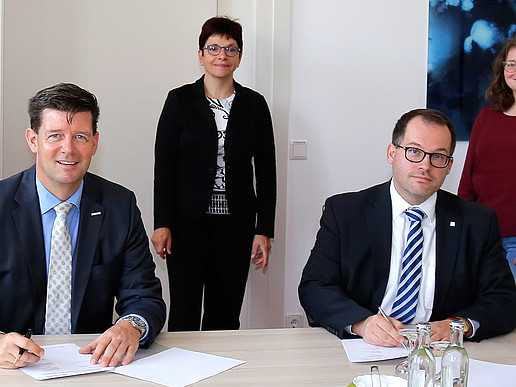 Frank Kebbekus and Prof. Dr. Alexander Kratzsch in the foreground at the signing of the contract. In the background, Chancellor Karin Hollstein and student Nicola Bell.