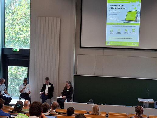 Four people are discussing the principles of good teaching on stage; the audience is listening to the conversation.