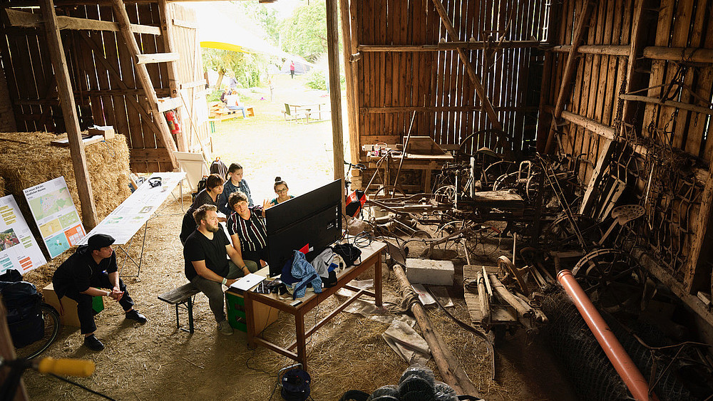 Symbolic image for the citizen science method "land inventory": several people working with modern technology in a barn.
