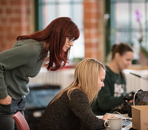 Employees in the lounge area checking the screen settings, looking at the laptop screen