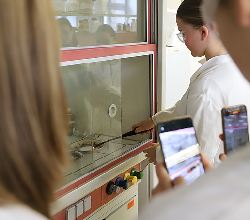 A pupil lights a substance in a small bowl under the extractor fan.