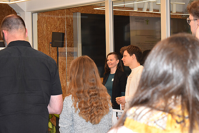 Workshop participants stand next to each other in the Celsiuz workroom and discuss a task.