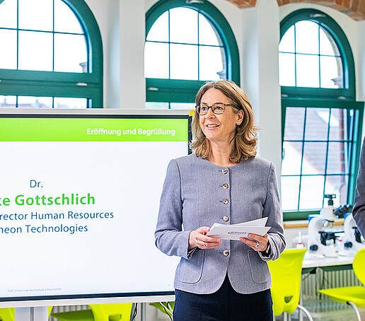 Eine Infineon-Mitarbeiterin stellt sich dem Publikum vor neben einem Bildschirm stehend.