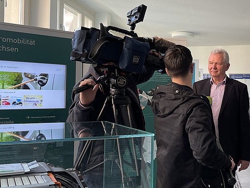 Im Vordergrund der Ausstellung, führen ein Kameramann und ein Reporter ein Interview mit Professor Haim. 