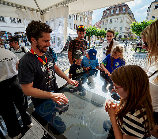 An HSZG employee explains the wiping table to visitors to the stand.