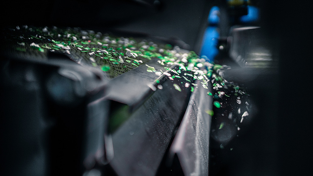 Snippets of green fly out of a machine.
