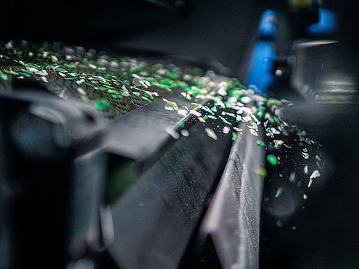 Snippets of green fly out of a machine.