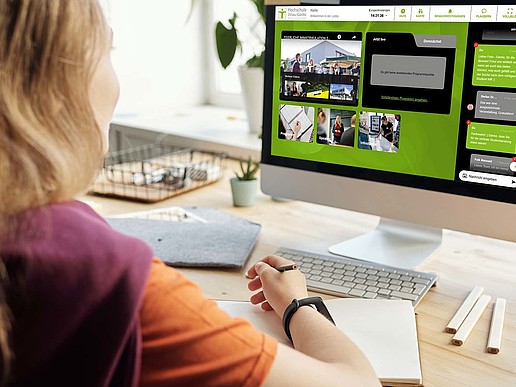 Eine junge Frau sitzt am Schreibtisch. Auf dem PC-Bildschirm vor ihr ist die Online-Plattform des Hochschulinfotages der HSZG eingeblendet.