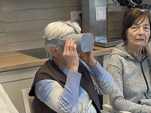 An old lady is wearing VR glasses, two old ladies are sitting to her left and right.
