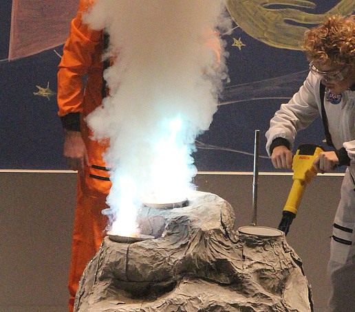 An employee in a spacesuit drills at a stone.