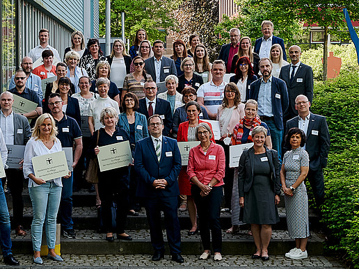 Eine Gruppe aus Hochschulmitgliedern und Kooperationspartnern aus dem Pflegebereich steht neben der Blue-Box am Campus Görlitz.