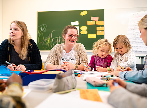 Mehrerer weibliche Studentin, wobei 2 Ihre kleinen Töchter neben sich sitzen haben. Alle befinden sich in einem Seminar.