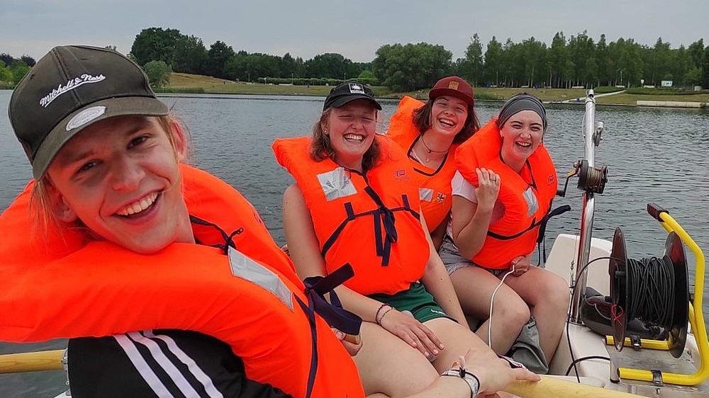 Studierende sitzen mit Rettungswesten im Boot.