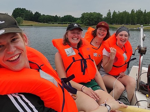 Students sit in the boat with life jackets.