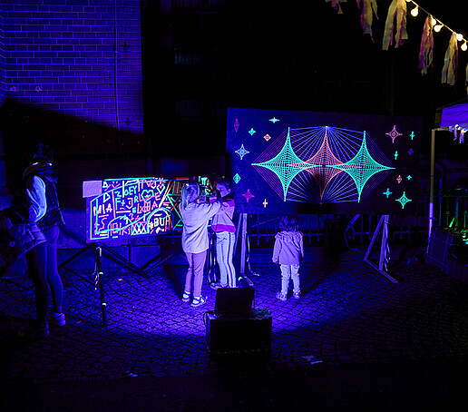 Children paint with neon colors on a canvas.