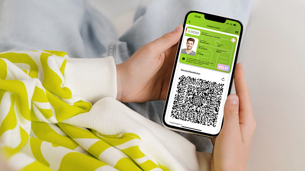 A smartphone lies in two palms, the digital student ID can be seen on the display.