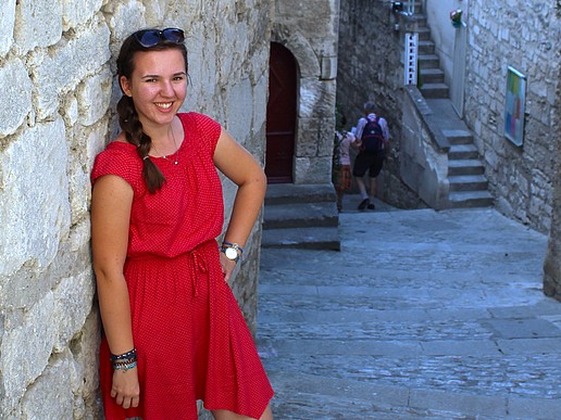 Anna Grohmann lehnt sich lächelnd an eine Wand an.