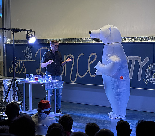 A team member in an inflatable polar bear costume talking to the dance instructor.