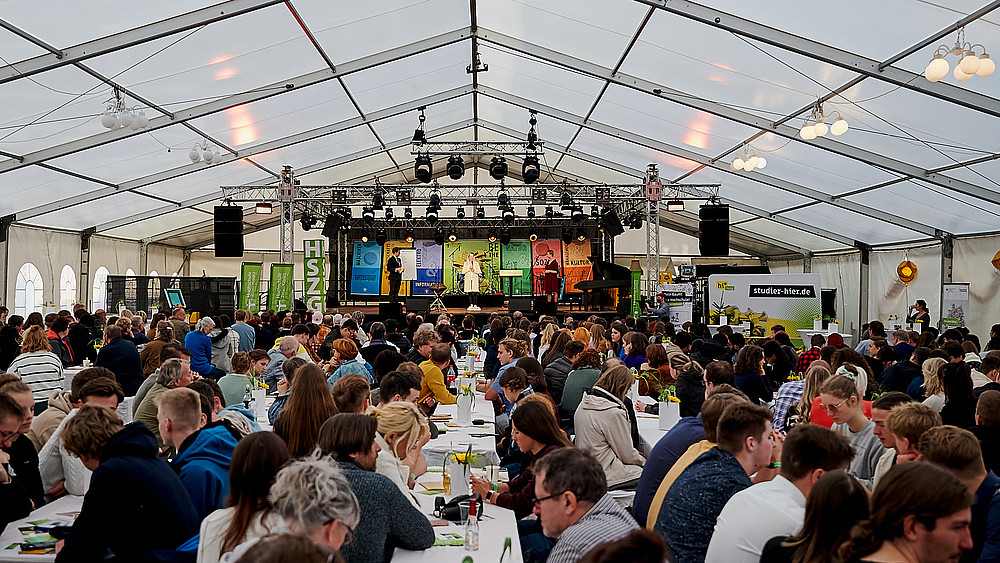 Im Festzelt sitzen hunderte Gäste auf Bierzeltgarnituren.