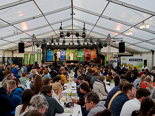 Im Festzelt sitzen hunderte Gäste auf Bierzeltgarnituren.