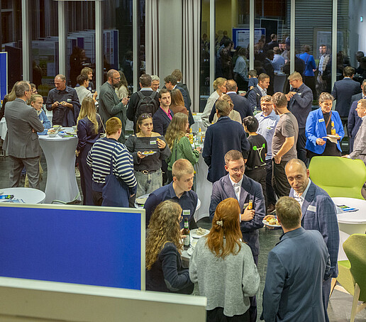 The guests chat in the auditorium and are surrounded by a poster exhibition.