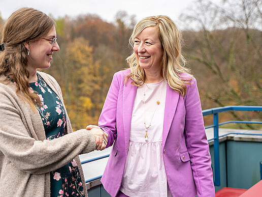 Claudia Döring and Professor Keil shake hands on a roof terrace.