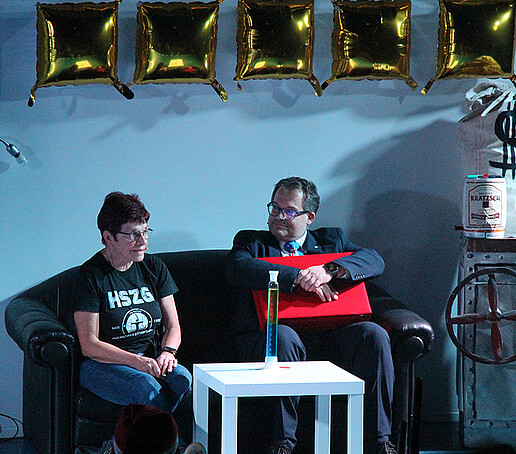 Mrs. Hollstein and the principal are sitting on the couch.