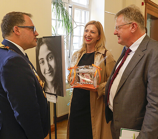 The principal talks to two guests who present him with a gift.