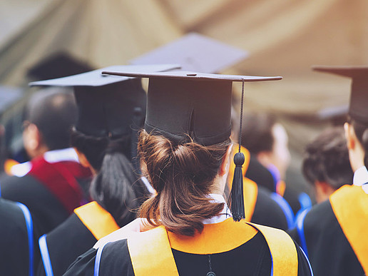 A row of doctoral candidates in festive attire with doctoral hats.