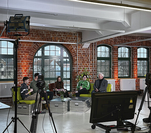 Im Celsiuz ist ein TV-Studio mit grünen Sofas aufgebaut. Bildschirme und Monitore stehen im Vordergrund.