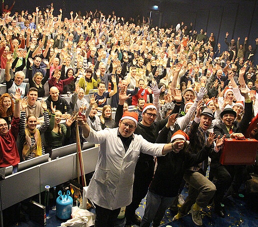 The audience and the performers cheer into the camera.