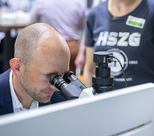 The district administrator looks through a microscope.