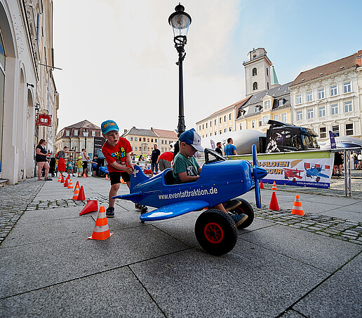Children try out a blue toy airplane.