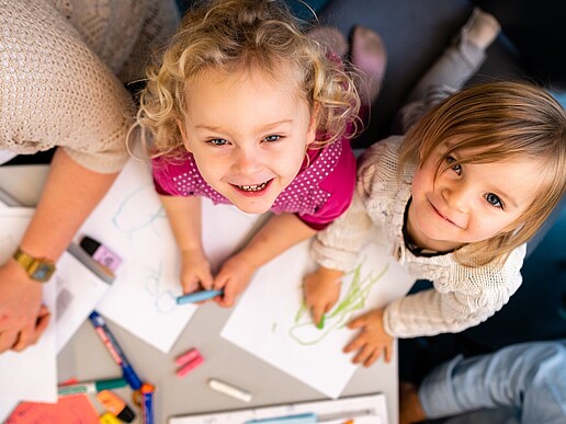 Zwei Kindergartenkinder lachen in die Kamera.