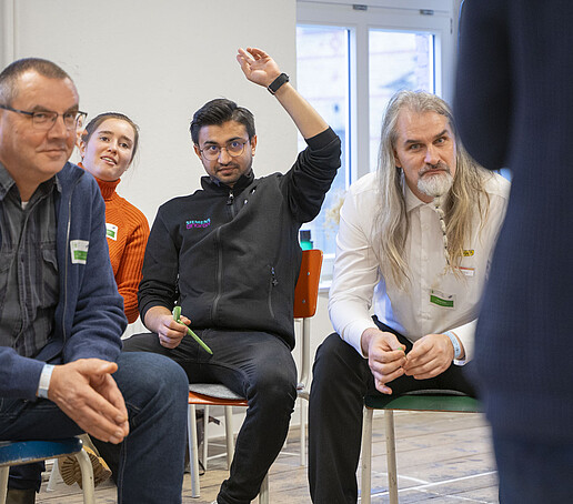 A group discusses. One holds up his hand.