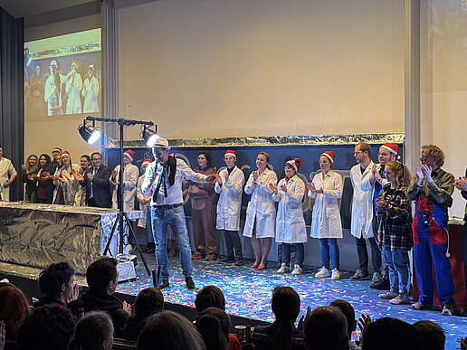 The show lecture team stands in a row on the lecture hall podium and applauds.