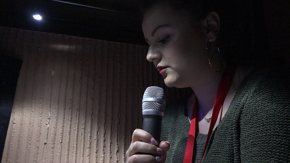 Student Agata speaks into a microphone in a darkened room.