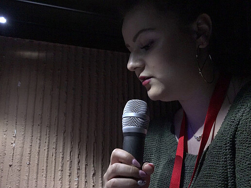 Student Agata speaks into a microphone in a darkened room.