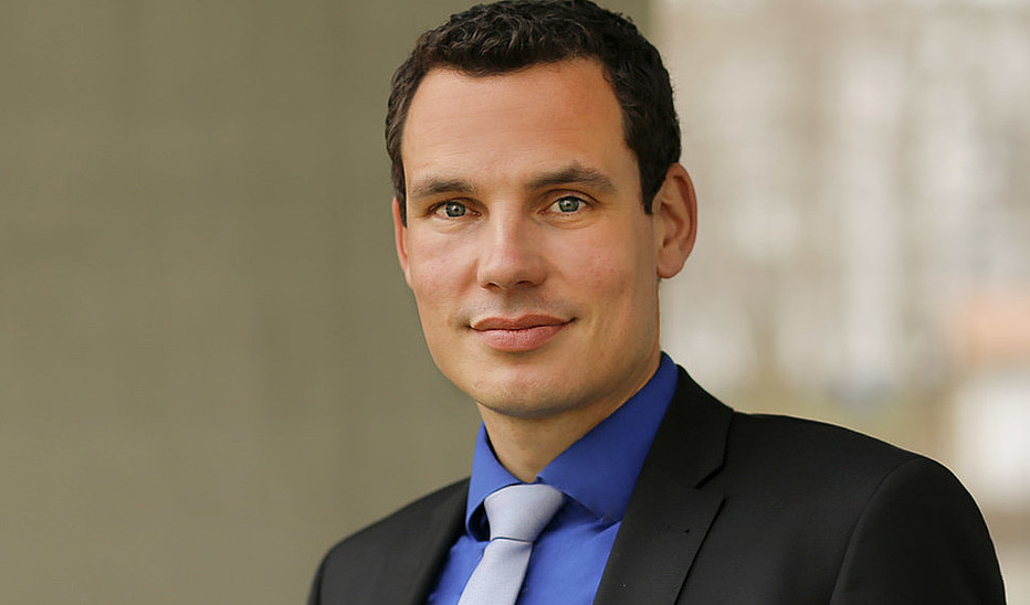Foto: HSZG Professor Erik Hahn trägt einen Anzug und lächelt in die Kamera.
