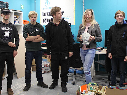 A group of pupils stand in the workroom with the smiling principal.