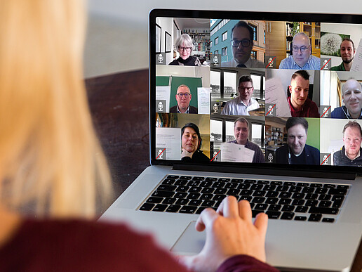 Several IPWB participants and congratulators can be seen on a screen. A blonde woman sits in front of the laptop.