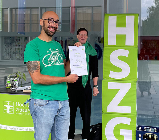 An employee holds his certificate up to the camera and smiles.