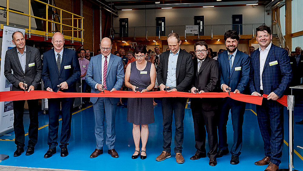 Several people cut a red ribbon