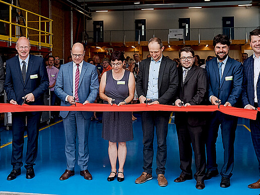 Several people cut a red ribbon
