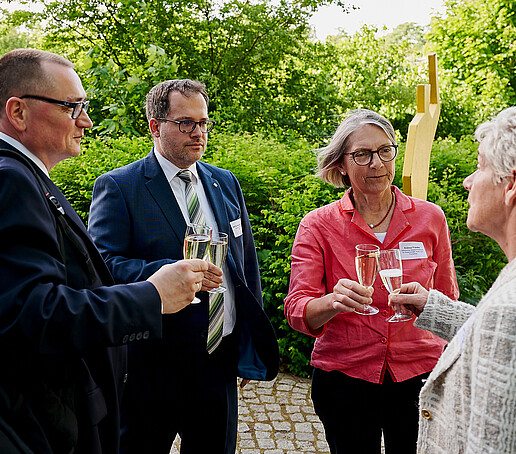 Prof. Knoll, Prof. Kratzsch, Dr. Franke and Ms. Martina Weber toast together with champagne glasses outside.